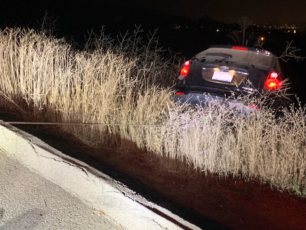 A black car drove off the road and is getting a tow to a repair shop